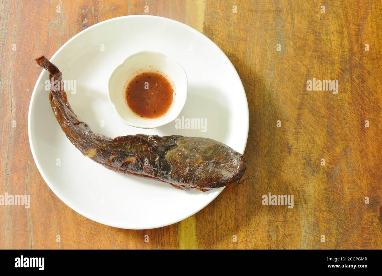 immersione di pesce gatto alla griglia con salsa piccante su piatto Foto Stock