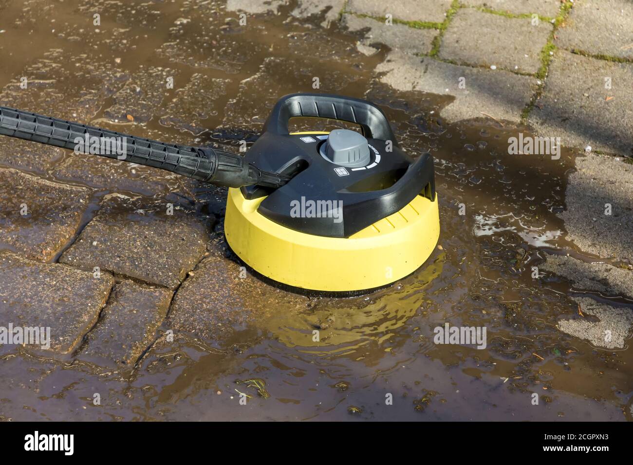 Pulire le pietre di pavimentazione della terrazza con detergente per superfici e pulitore ad alta pressione Foto Stock