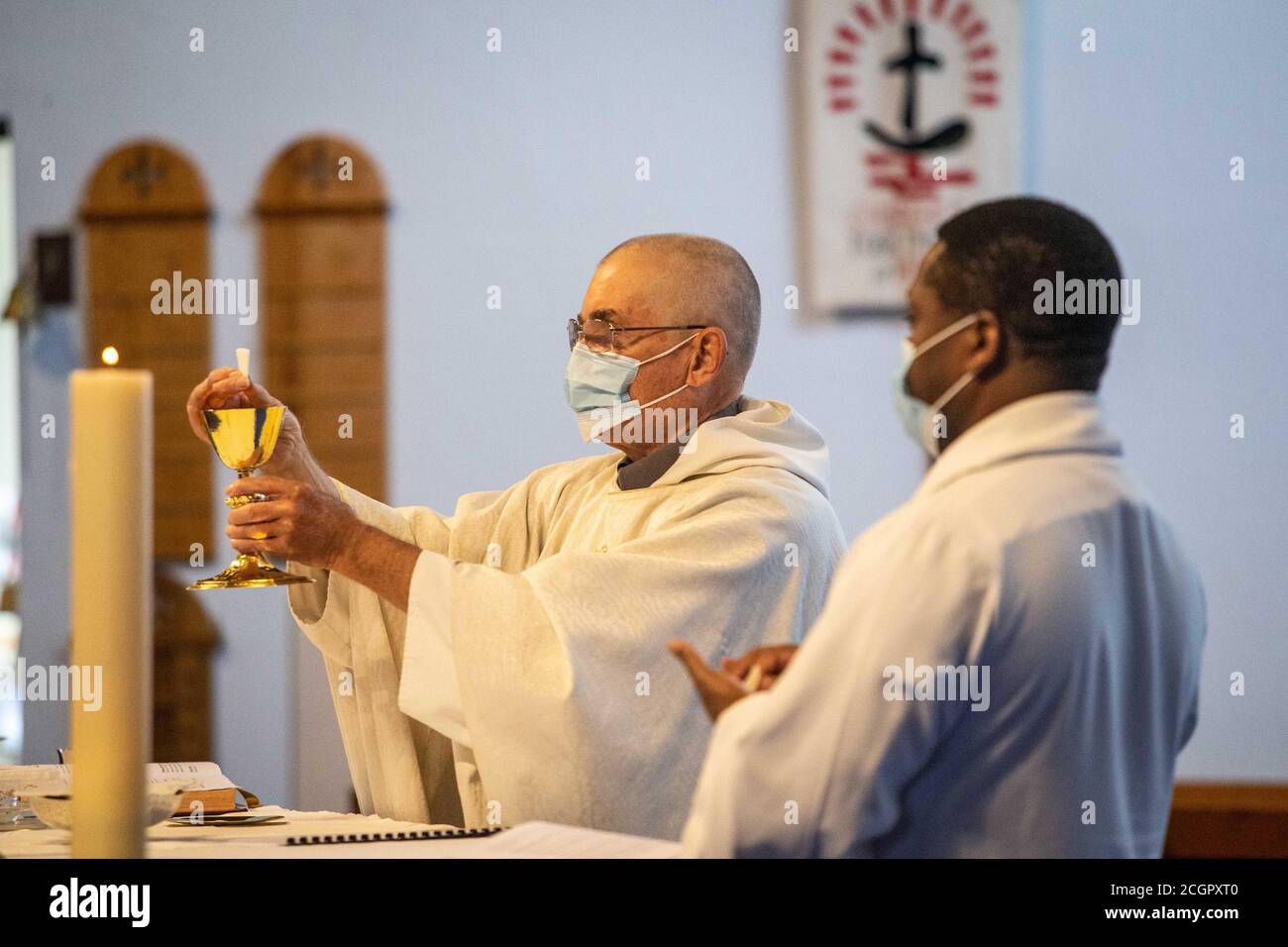 Sacerdote cattolico che prepara la Santa comunione indossando la maschera di messa Durante la pandemia di Coronavirus / Covid 19 in Inghilterra UK 2020 Foto Stock