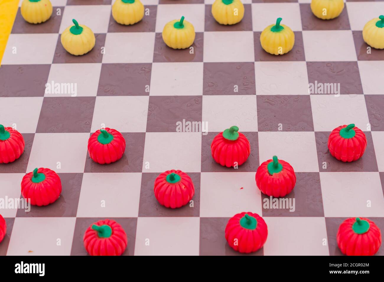 primo piano della tavola a scacchi con dama di zucca, sfondo colorato Foto Stock