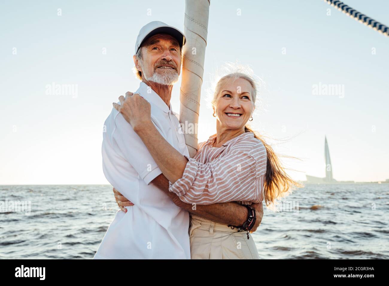 Due persone mature in piedi su albero a vela e abbracciare l'uno con l'altro Foto Stock