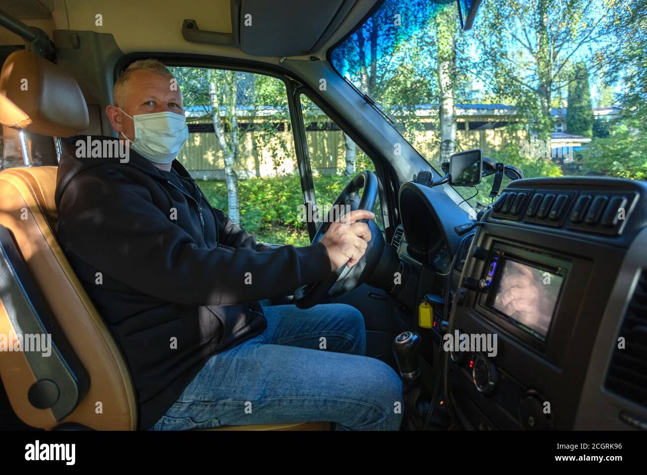 Driver in una maschera medica conduce un bus nero Guida sicura durante una pandemia, protezione contro il coronavirus. Foto di alta qualità Foto Stock