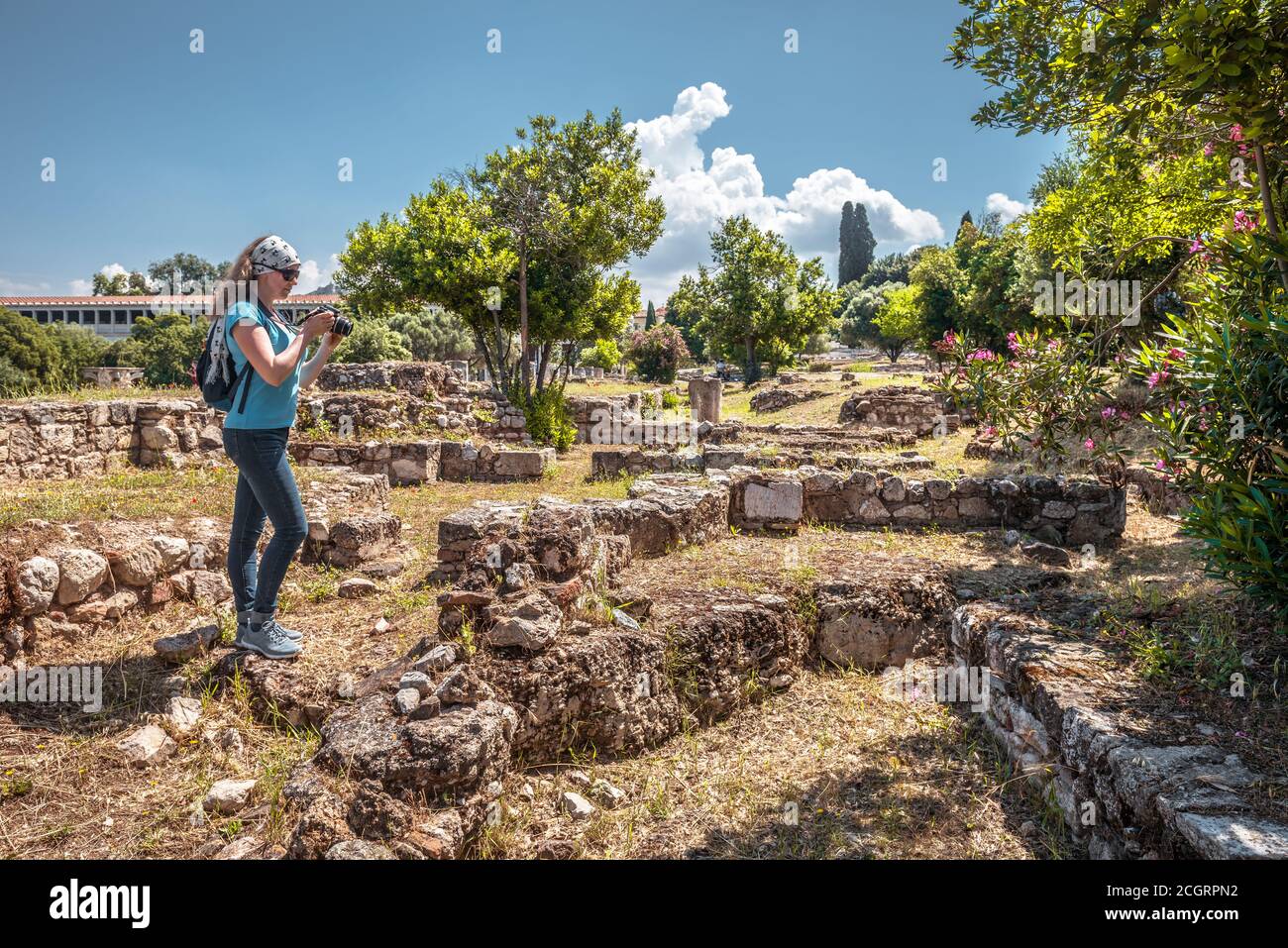 Donna turistica in Agora antica, Atene, Grecia. Questo posto e' un famoso punto di riferimento di Atene. Giovane bella donna fotografa le rovine greche classiche in Atthe Foto Stock