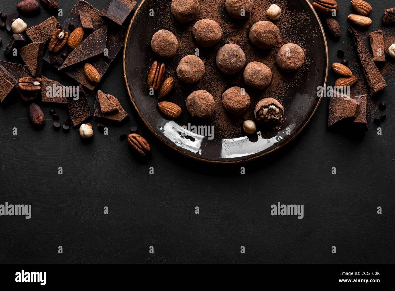 Tartufi al cioccolato con cioccolato fondente e noci su sfondo nero, vista  dall'alto, spazio per