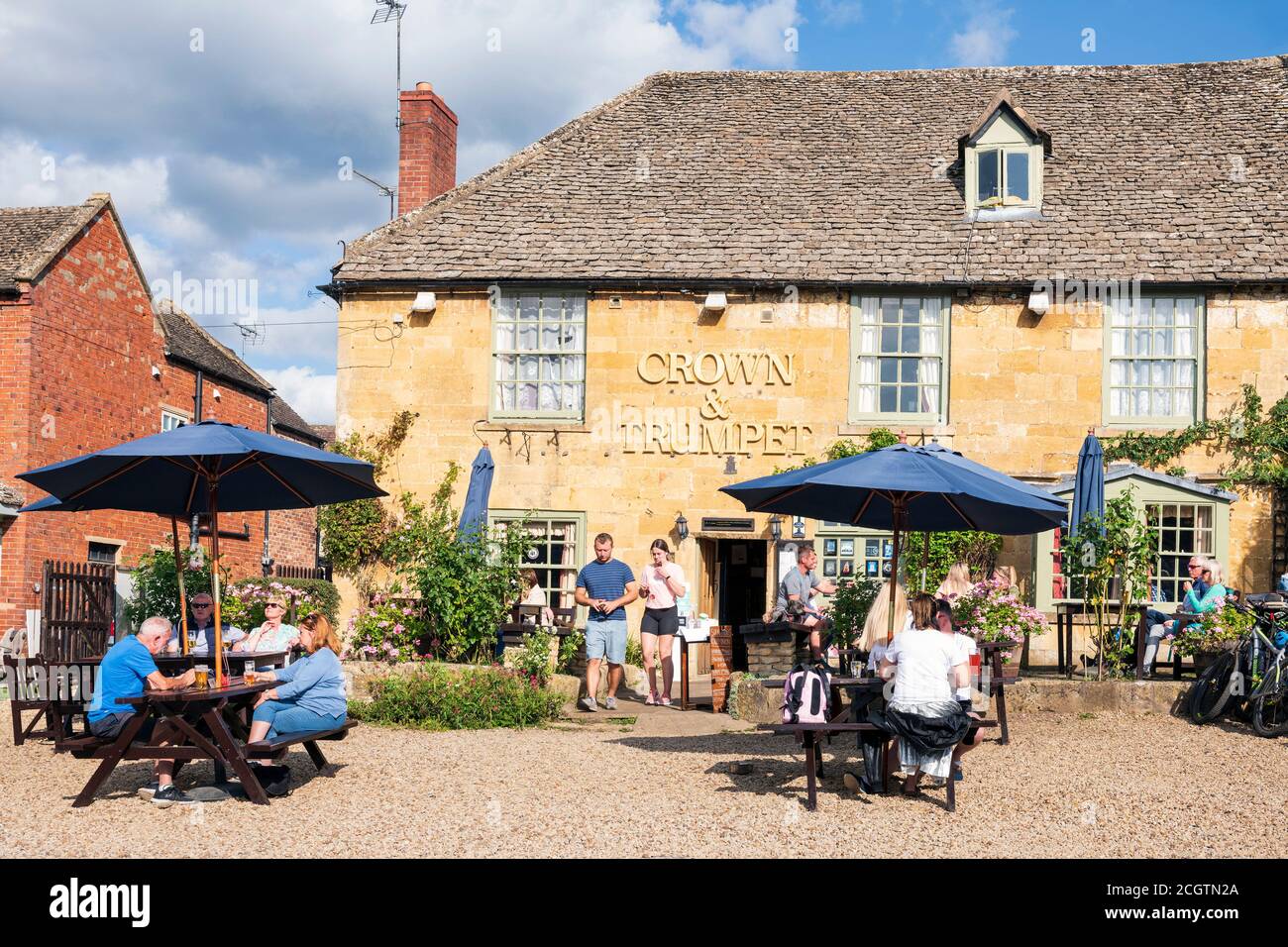 Cotswolds pub The Crown & Trumpet con persone che bevono all'aperto in una giornata di sole. Turisti in un pub birreria all'aperto, Broadway, Inghilterra, Regno Unito. Foto Stock