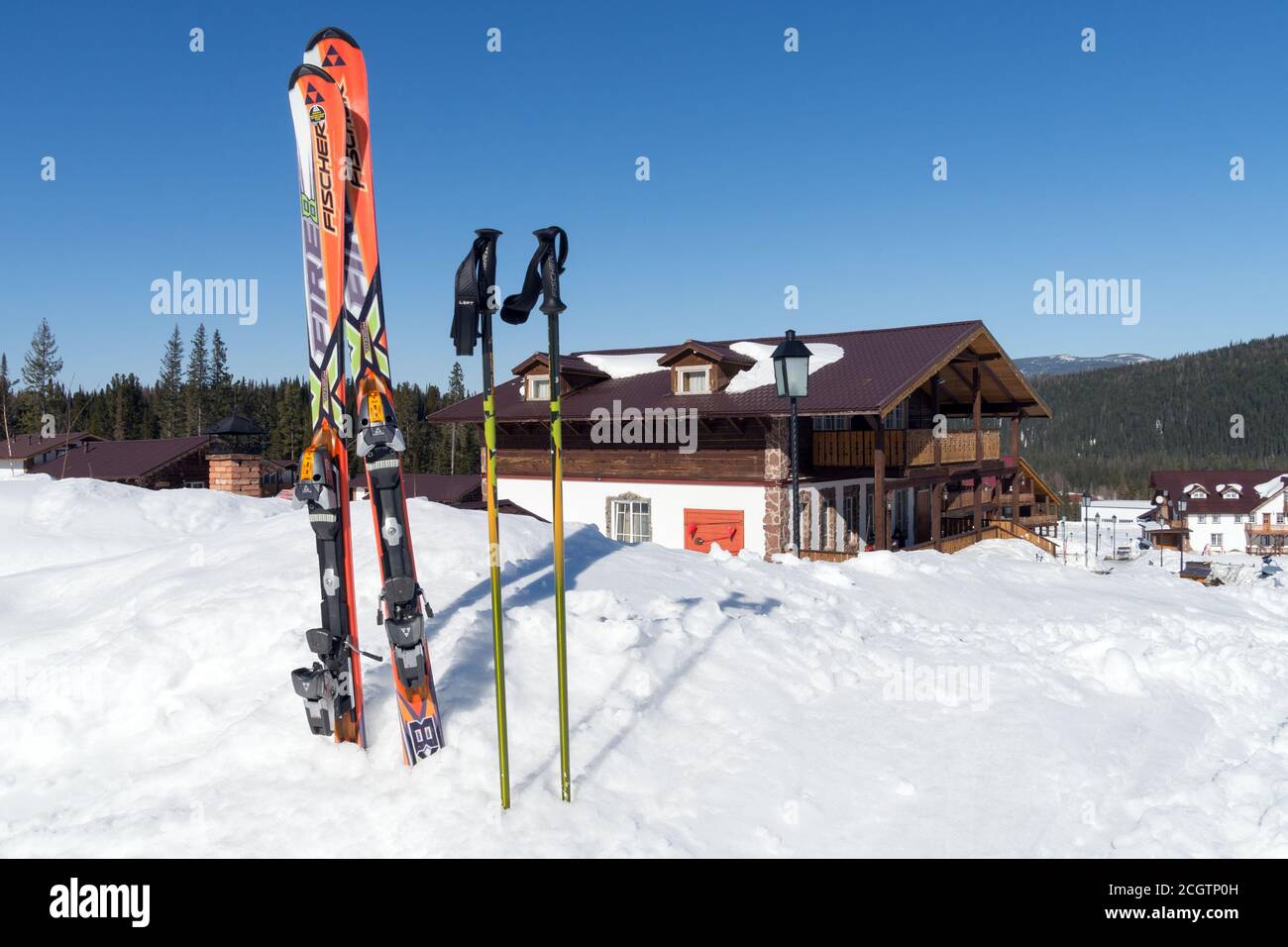 Lo sci alpino con bastoni si trova in una deriva bianca sullo sfondo della casetta svizzera. Foto Stock