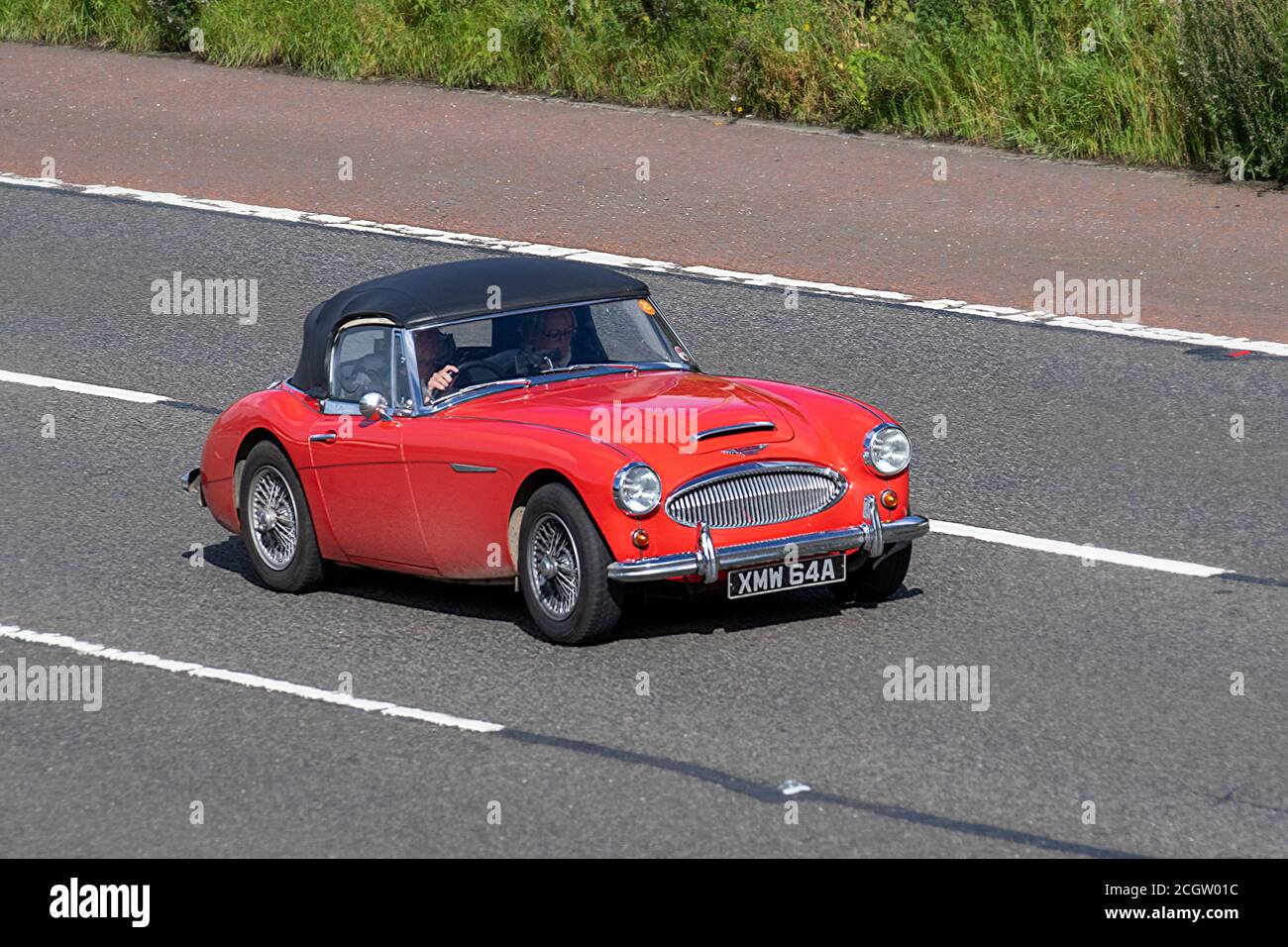 1963 rosso Austin-Healey 3000 Mark II BJ7 Sport Convertibile; veicoli in movimento veicolare, automobili anni '60 che guidano veicolo su strade del Regno Unito, motori, motori sulla rete autostradale M6. Foto Stock