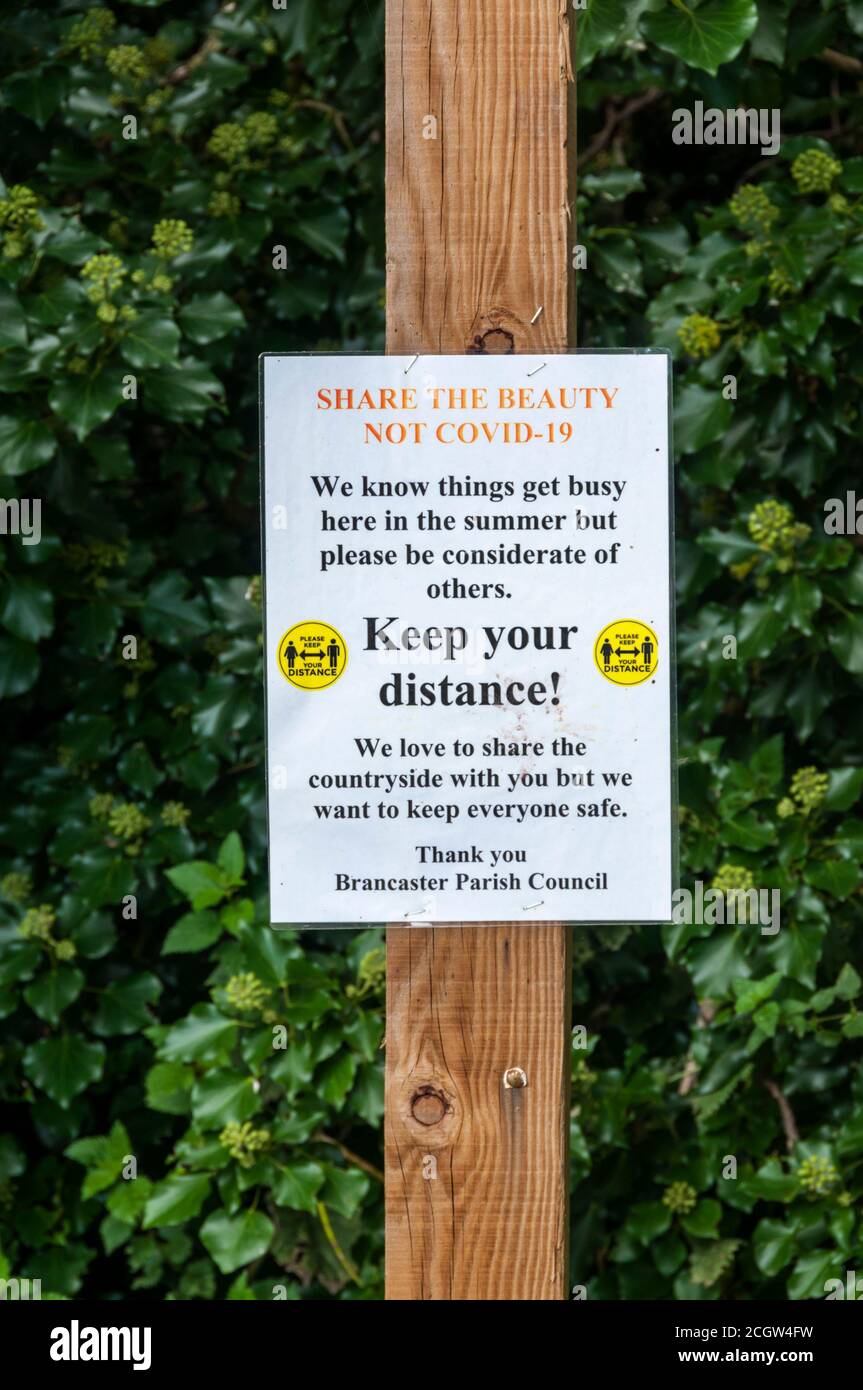 Un segno che incoraggia l'allontanamento sociale durante la pandemia di coronavirus. A Brancaster sulla costa nord del Norfolk. Foto Stock
