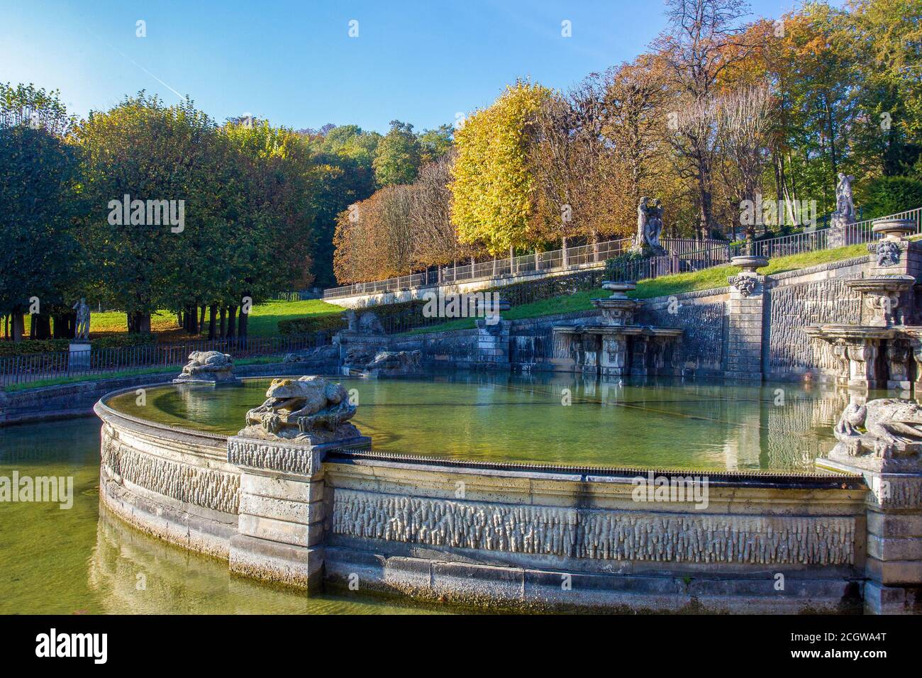 Idilliaca vista su Domaine National de Saint-Cloud - autunno fogliame di alberi . Fontana con monumenti di rane e persone a distanza Foto Stock