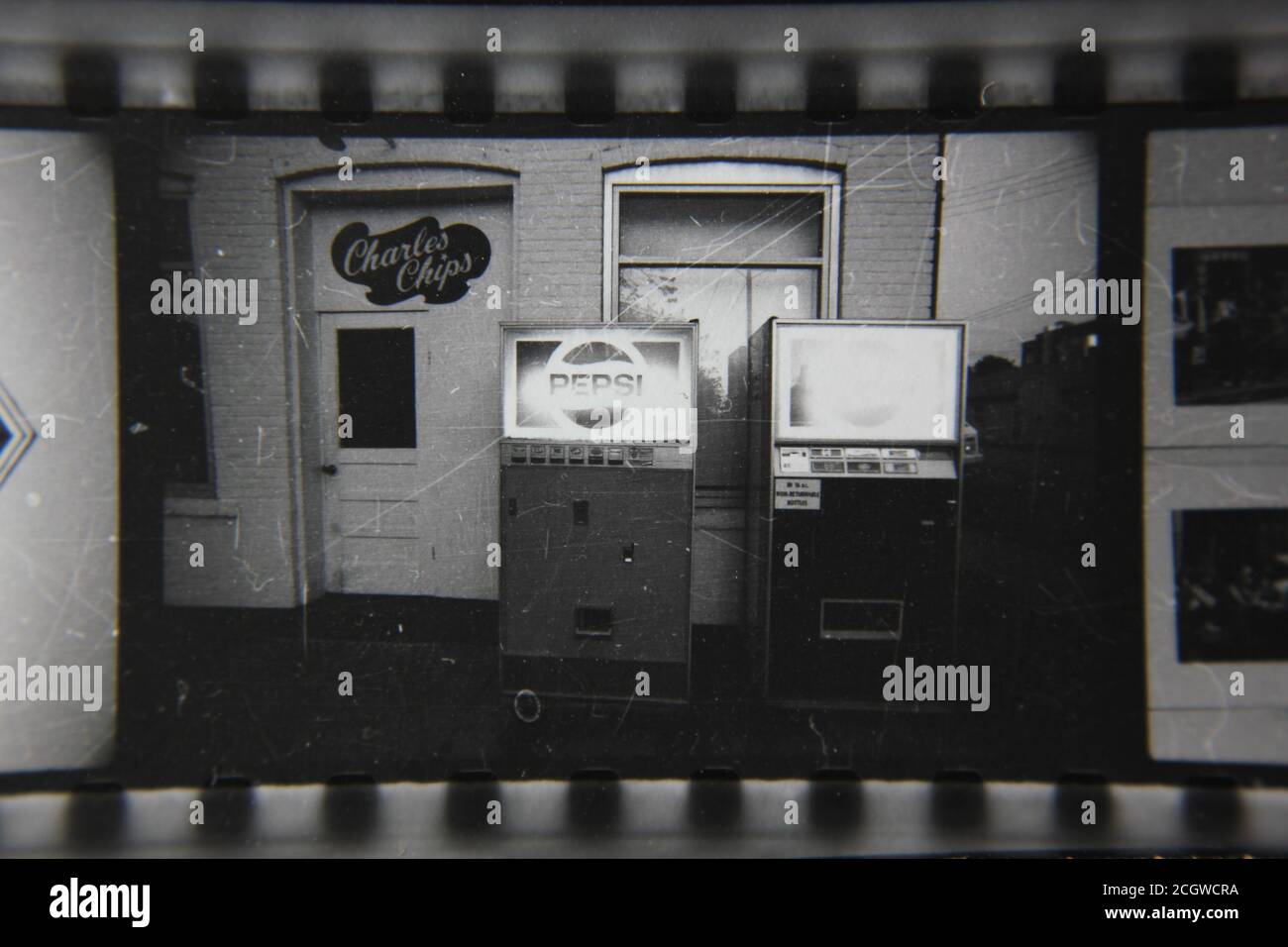 Ottima fotografia in bianco e nero degli anni '70 di vecchi distributori automatici che servono bevande Pepsi e patatine Charles. Foto Stock
