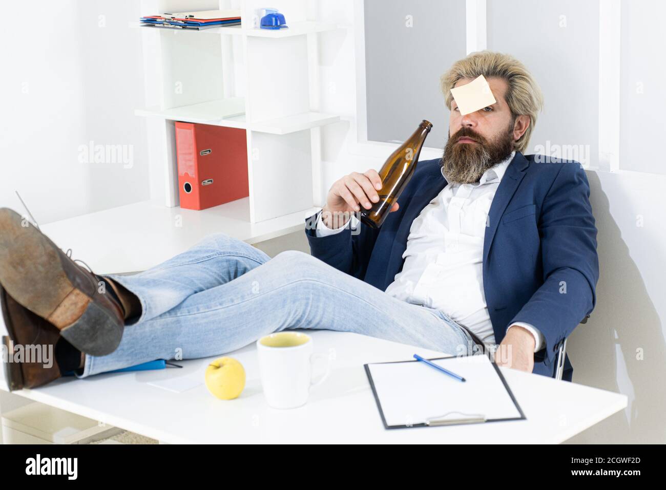 Un uomo d'affari ubriaco annoiato in ufficio alla fine della giornata lavorativa. Uomo d'affari che beve dallo stress. Foto Stock