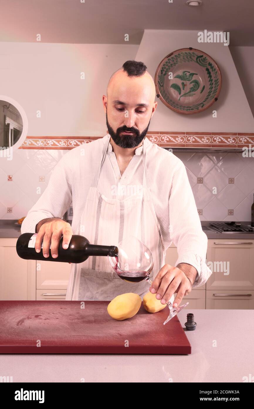 Chef maschio caucasico che si serve vino rosso Foto Stock