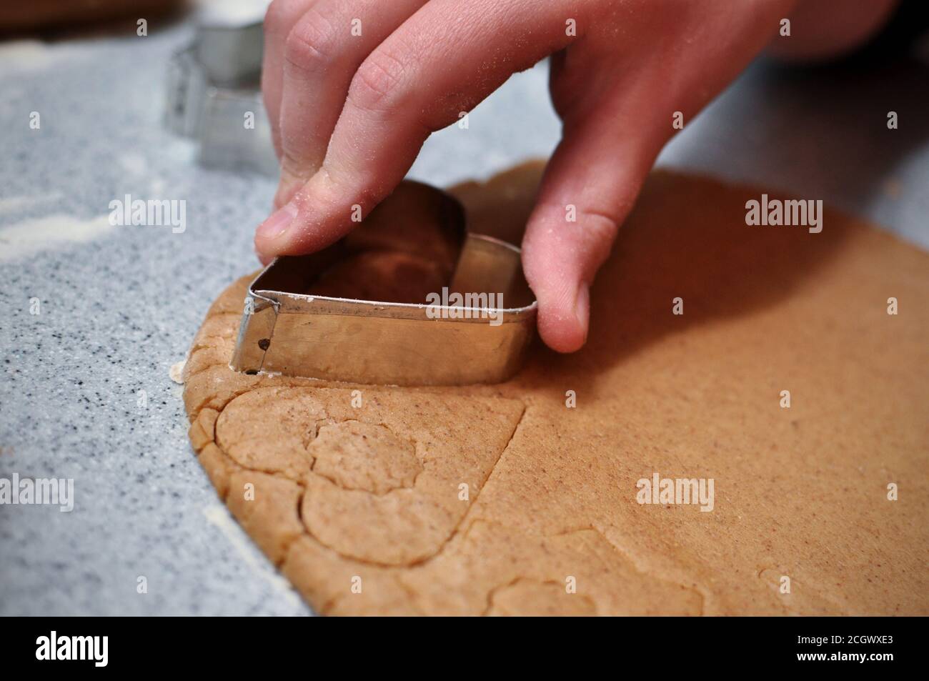 Mani di bambino usando le muffe di natale sull'impasto, immagine di closeup Foto Stock