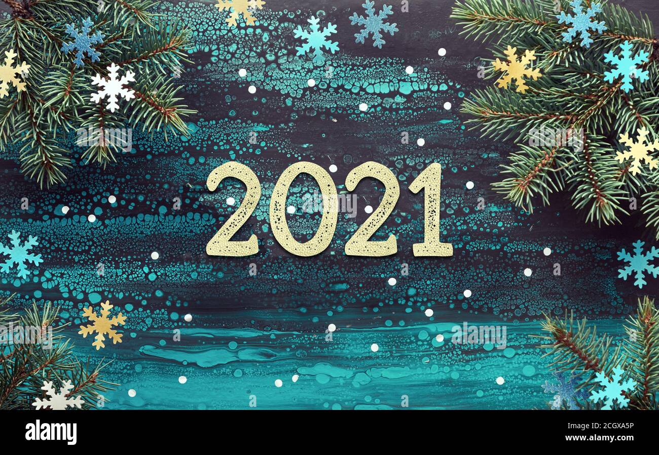 Felice anno nuovo 2021 sfondo festivo invernale con ramoscelli di abete, fiocchi di neve di carta giallo, blu e turchese. Disposizione piatta, vista dall'alto sul turchese a fluido dell'arte Foto Stock
