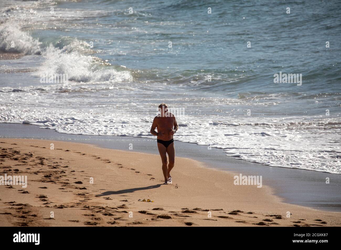 L'uomo di mezza età su una spiaggia di Sydney si esercita la mattina presto, Sydney, Australia Foto Stock