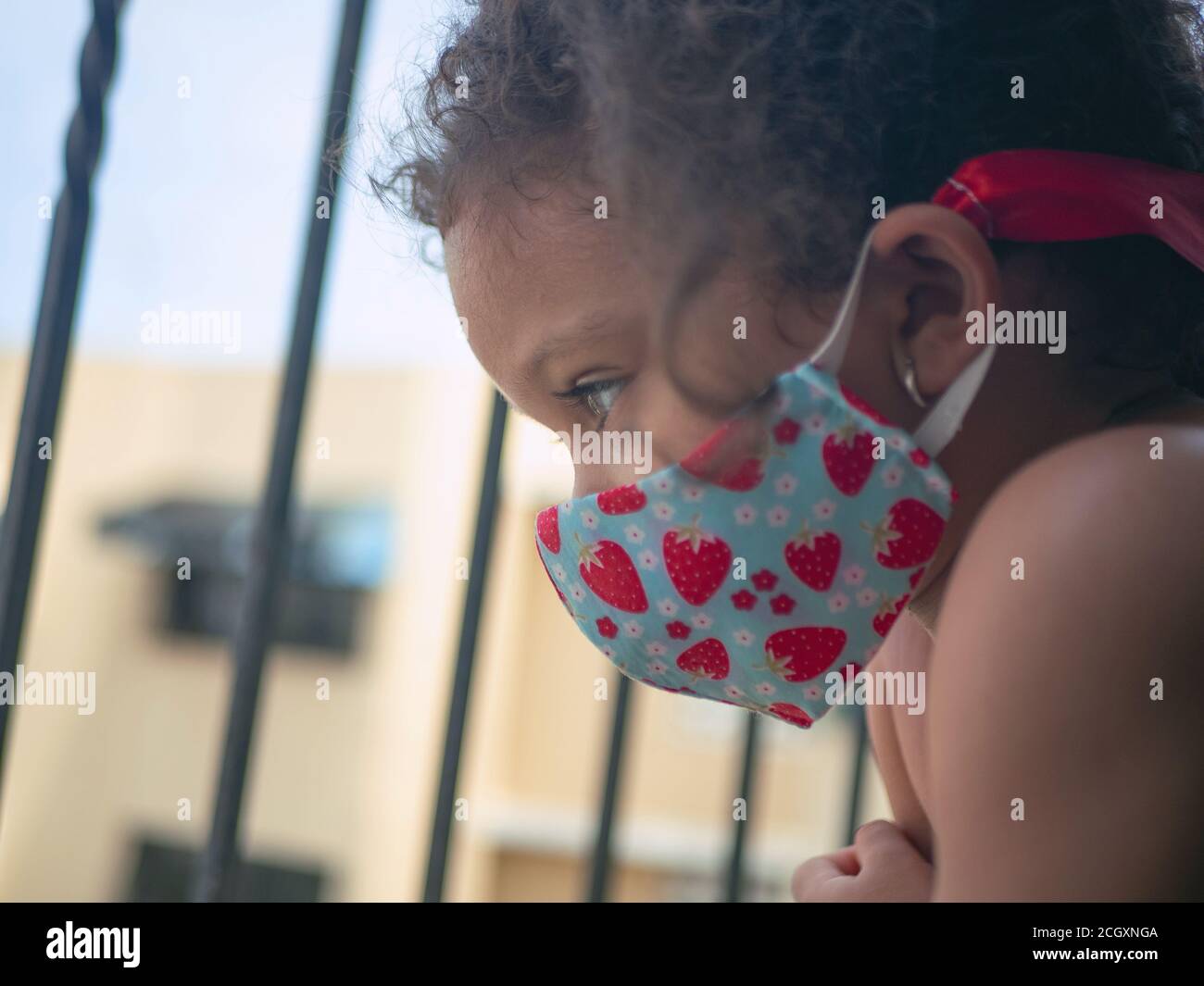 Una bambina con una maschera di cuori sta guardando esterno Foto Stock