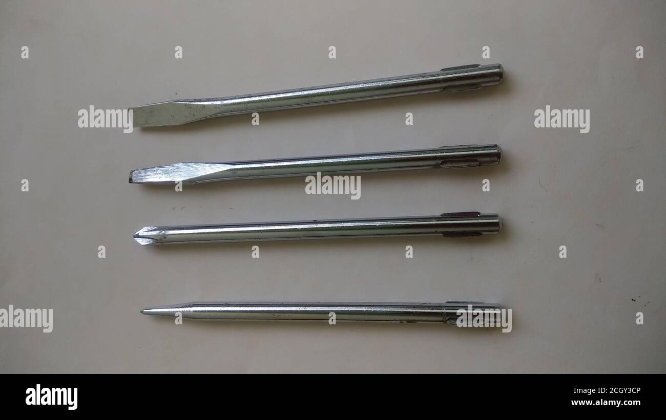 Quattro diversi cacciaviti metallici su fondo bianco con messa a fuoco selettiva. Utensili metallici industriali. Utensili di riparazione. Foto Stock