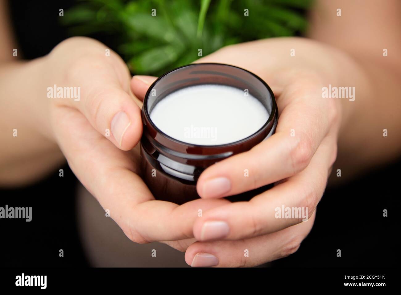 Burro di karité biologico nelle mani, cosmetici naturali idratanti, prodotti per la cura della pelle e dei capelli. Trattamento anti-invecchiamento. Foto Stock