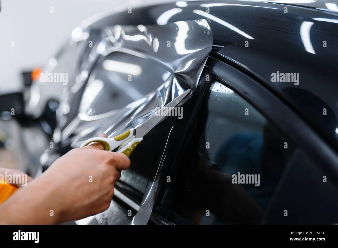 Il lavoratore tiene la pellicola, l'installazione di tintura dell'automobile Foto Stock