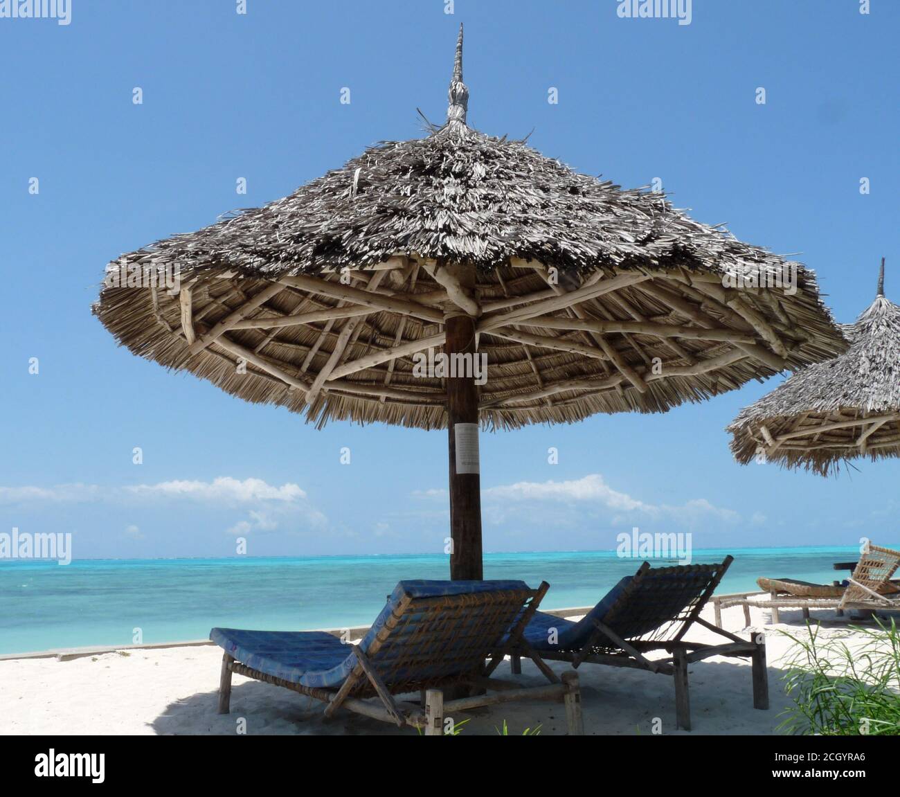 Ombrello di paglia e due lettini di legno da sole su UNA spiaggia tropicale, Zanzibar Foto Stock