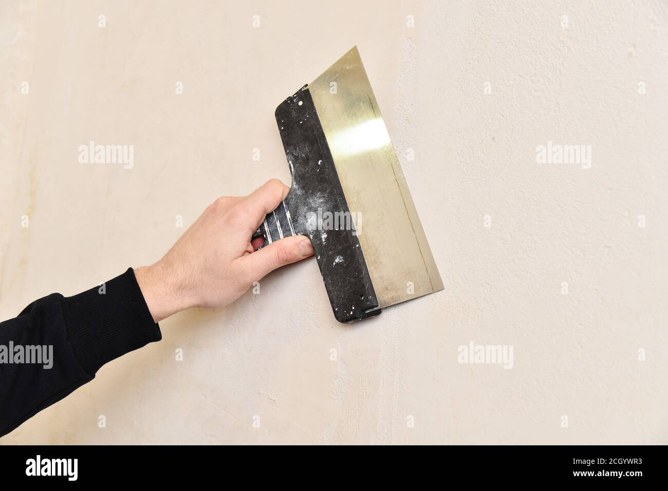 Lavori di riparazione, stucco della parete con una spatola. Porta a mano coltello per stucco, intonaco e stucco. Foto Stock