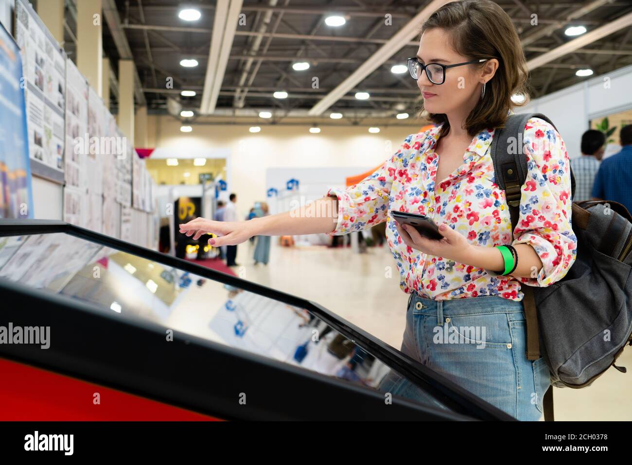 Una donna con telefono che utilizza un chiosco self-service senza contatto Foto Stock