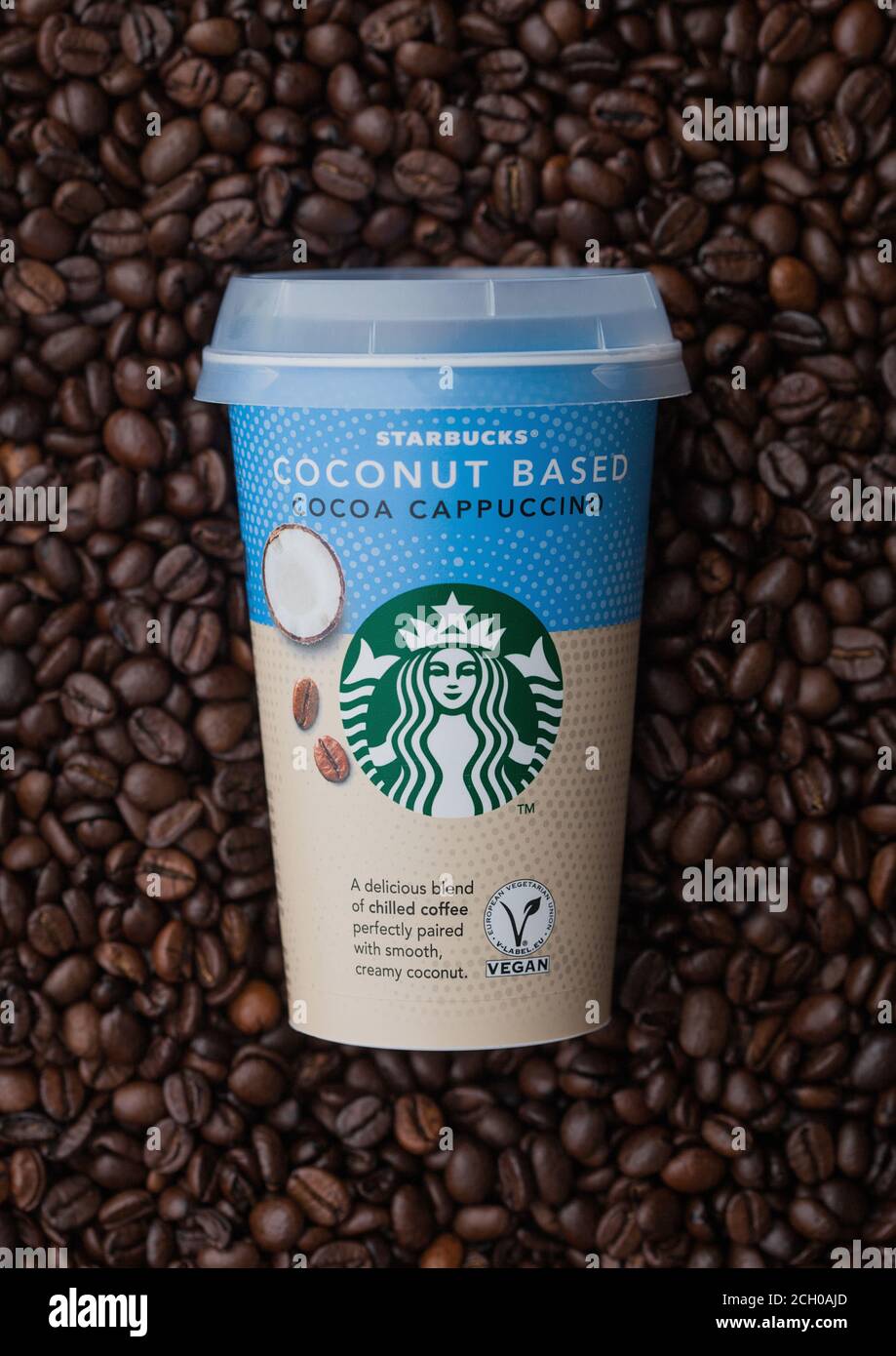 LONDRA, Regno Unito - 09 SETTEMBRE 2020: Tazza di carta di caffè freddo al cappuccino di cacao a base di cocco Starbucks sopra i chicchi di caffè crudo freschi. Foto Stock