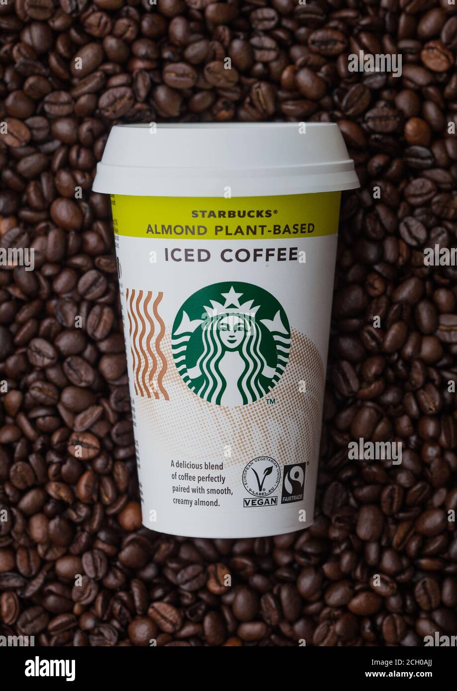 LONDRA, Regno Unito - 09 SETTEMBRE 2020: Tazza di carta di caffè freddo ghiacciato a base di Almond Plant Starbucks, sopra i chicchi di caffè crudo. Foto Stock