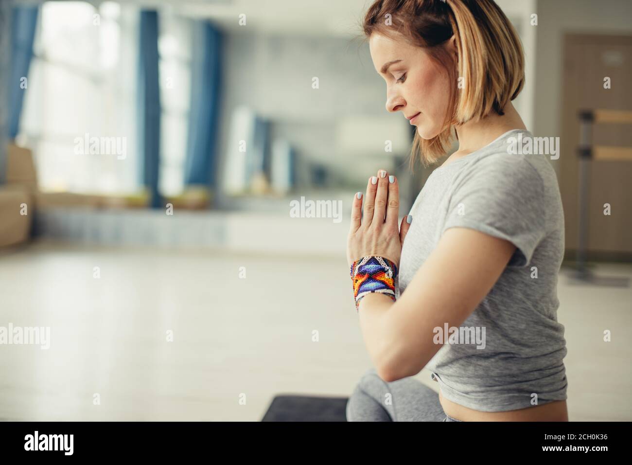 Profilo ritratto di giovane donna concentrata che lavora alla classe di yoga seduta in posizione facile, decente, piacevole con palme a Namaste, meditando, br Foto Stock