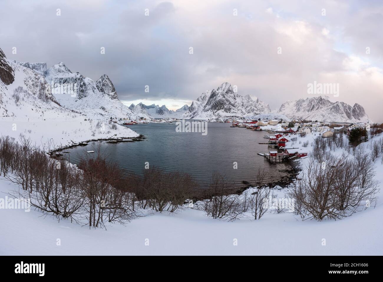 Bellissimo villaggio di Reine nelle Isole Lofoten in Norvegia. Coperta di neve paesaggio invernale al tramonto. Straordinaria attrazione turistica in circolo polare. Panora Foto Stock