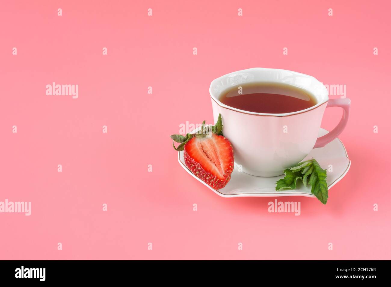 tazza di tè bianco con menta e fragole rosse mature su sfondo rosa. vista dall'alto. primo piano Foto Stock