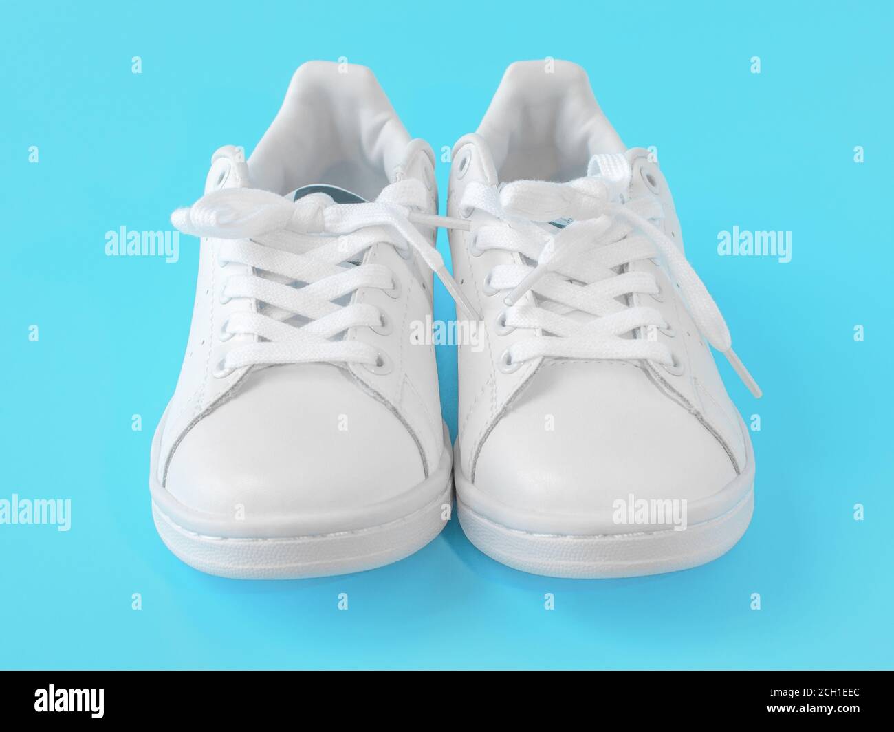 Paio di nuove sneaker bianche su sfondo blu. Nuove scarpe sportive in pelle bianca. Scarpe sportive per running, tennis, jogging. Sneaker bianche pulite Foto Stock