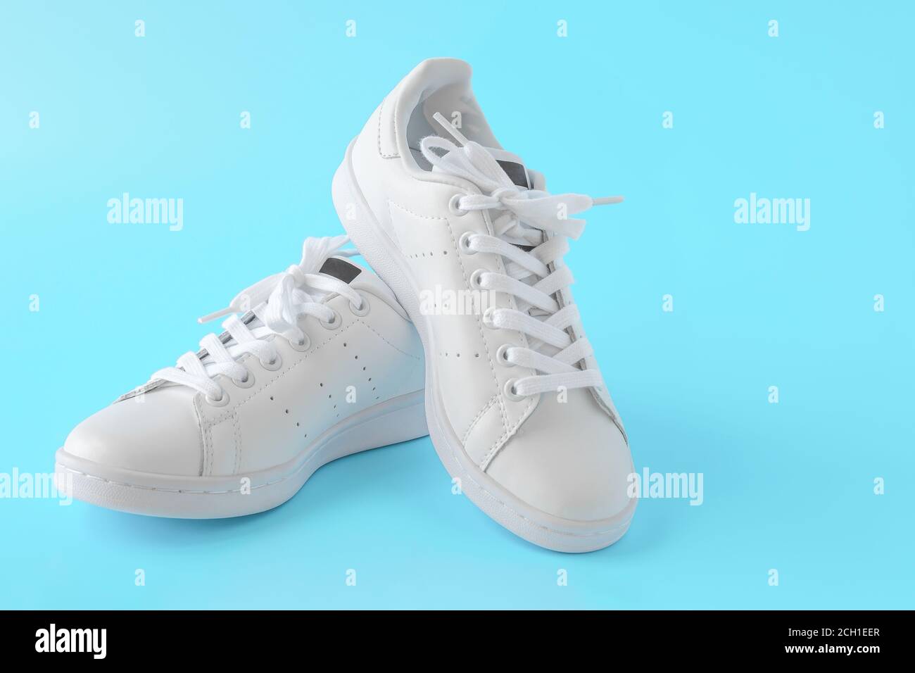 Paio di nuove sneaker bianche su sfondo blu. Nuove scarpe sportive in pelle bianca. Scarpe sportive per running, tennis, jogging. CopySpace Foto Stock