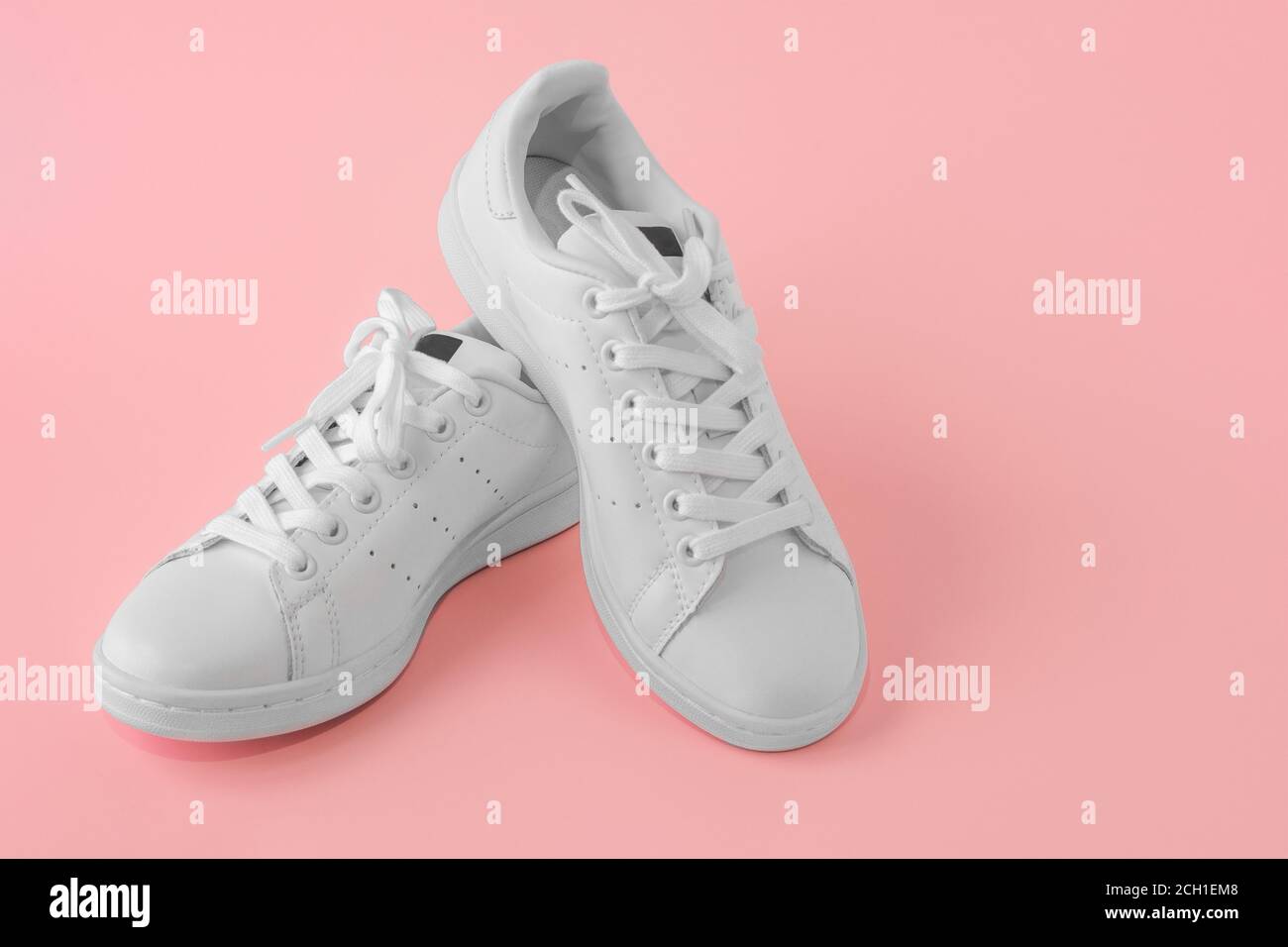 Paio di nuove sneaker bianche su sfondo rosa. Nuove scarpe sportive in pelle bianca. Scarpe sportive per running, tennis, jogging. CopySpace Foto Stock