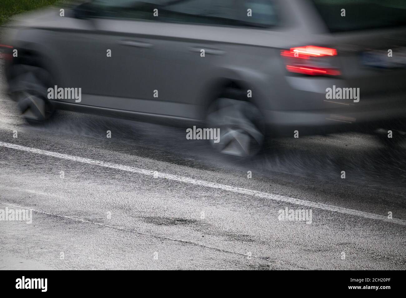 auto argentata che guida su una strada bagnata sotto la pioggia Foto Stock