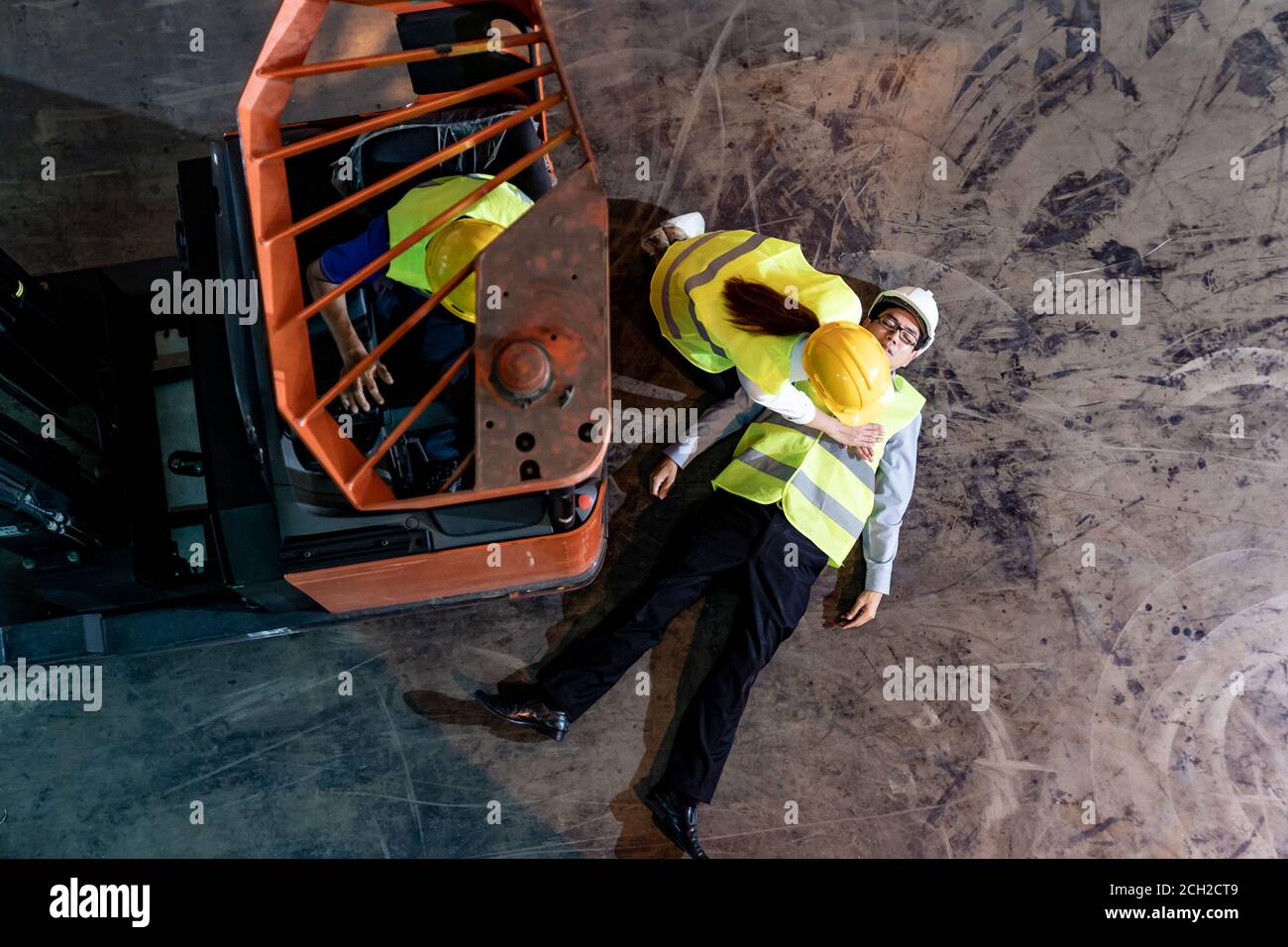 Il lavoratore asiatico esegue la rianimazione cardiopolmonare CPR dopo che il responsabile del magazzino si trova sul pavimento del magazzino dopo un incidente dal carrello elevatore. Uso per la sicurezza Foto Stock