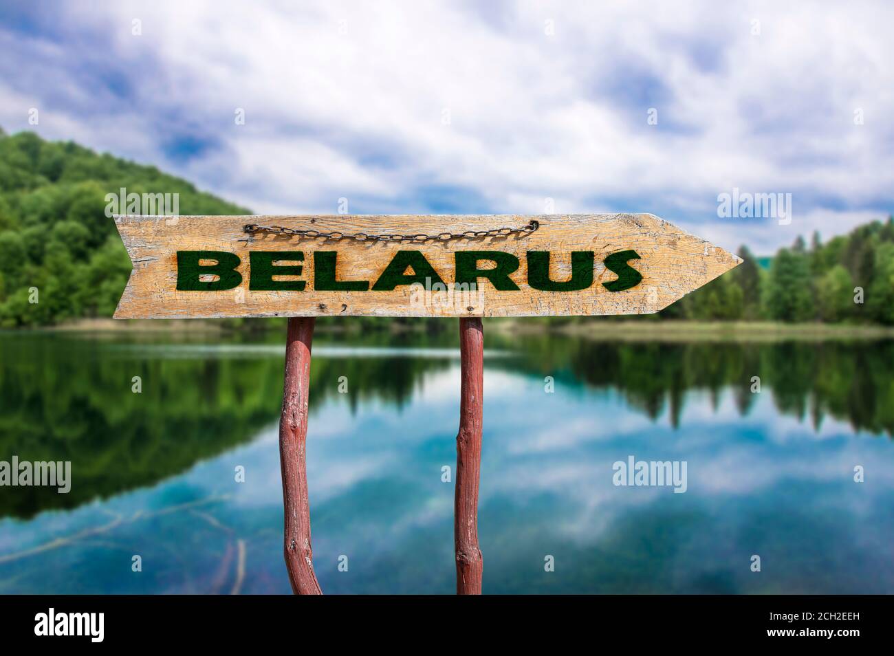 Belarus freccia di legno cartello stradale contro il lago nella foresta. Viaggio in Bielorussia Concept. Foto Stock