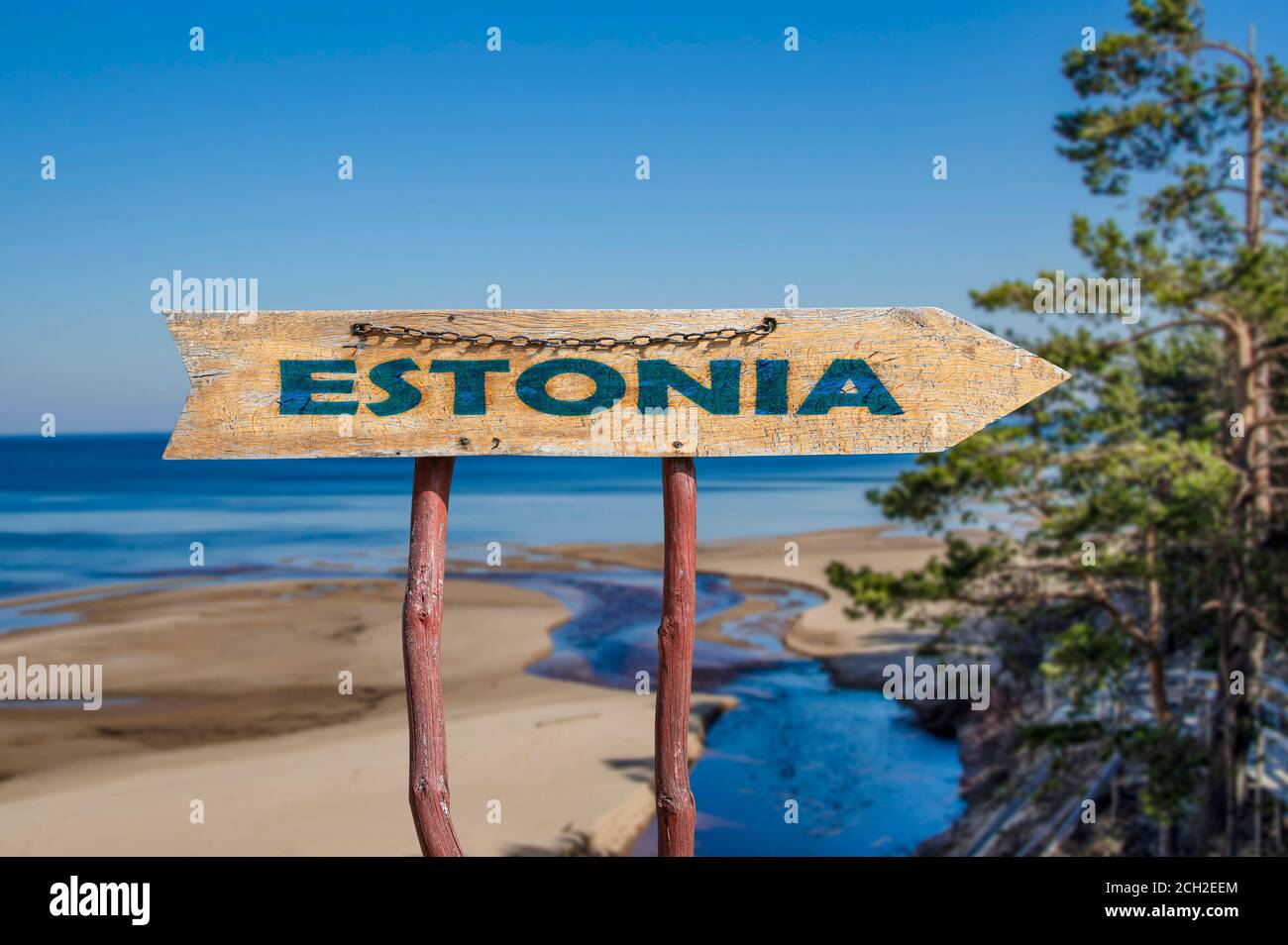Estonia freccia di legno segno sulla spiaggia del Mar Baltico e sfondo di alberi di pino. Viaggio in Estonia concetto. Foto Stock