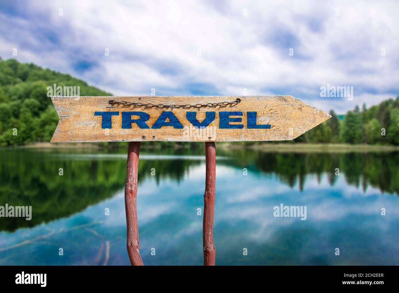 Viaggio freccia in legno segno strada contro il lago e la foresta vista. Concetto di viaggio. Foto Stock