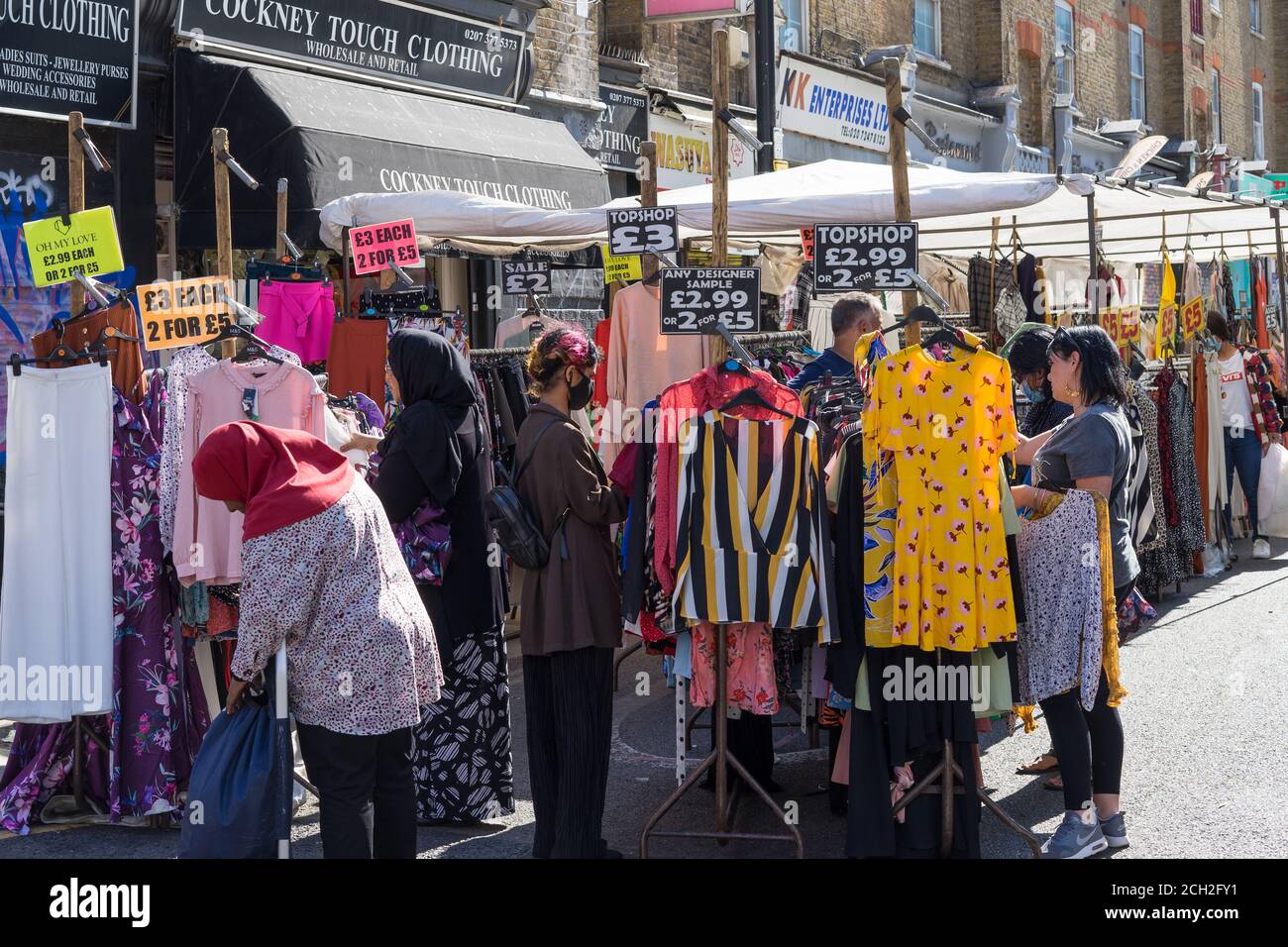 Acquirenti che guardano gli articoli su una bancarella di mercato. Petticoat Lane Market. Londra Foto Stock