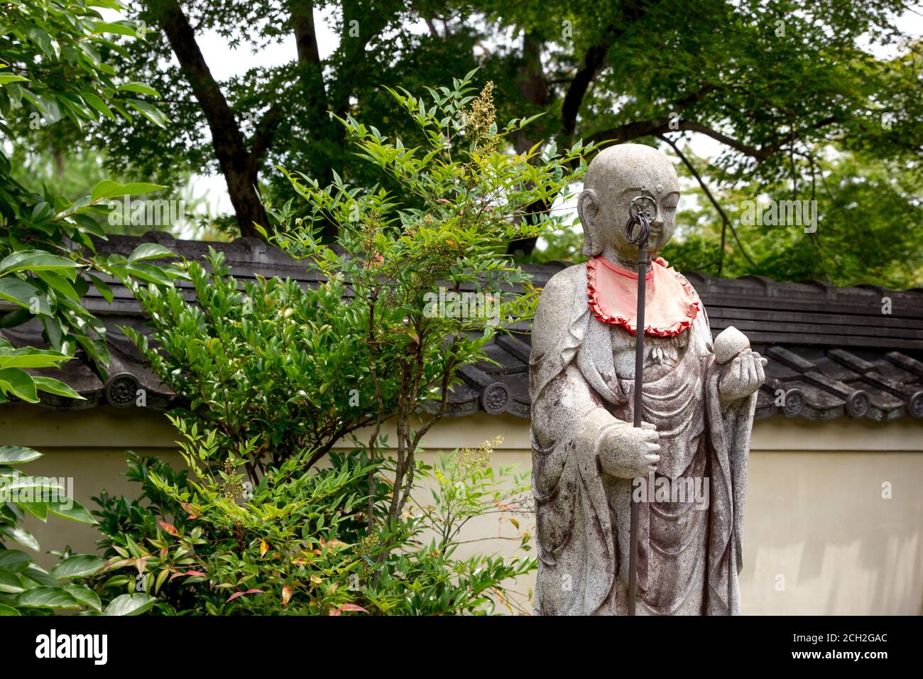 Arashiyama, Kyoto / Giappone - 21 giugno 2018: Pettorali rossi adornano le statue nei templi di Saga Arashiyama sulle colline occidentali di Kyoto. Foto Stock