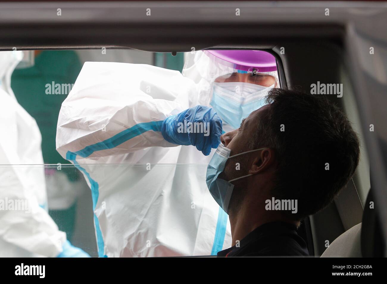 A Coruna-Spagna -18 agosto 2020: Un operatore sanitario utilizza un test PCR (bocca e tampone nasale) su una persona all'interno di un'auto un fiffirefighter Foto Stock