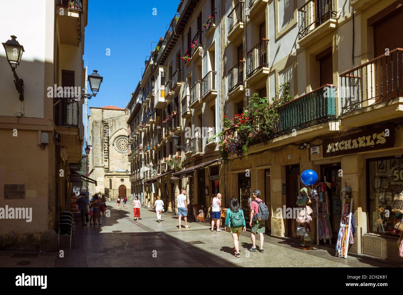 Donostia, Gipuzkoa, Paesi Baschi, Spagna - 12 Luglio 2019 : Passersby nel centro storico di Alde Zaharra. Chiesa di San Vicente sullo sfondo. Foto Stock