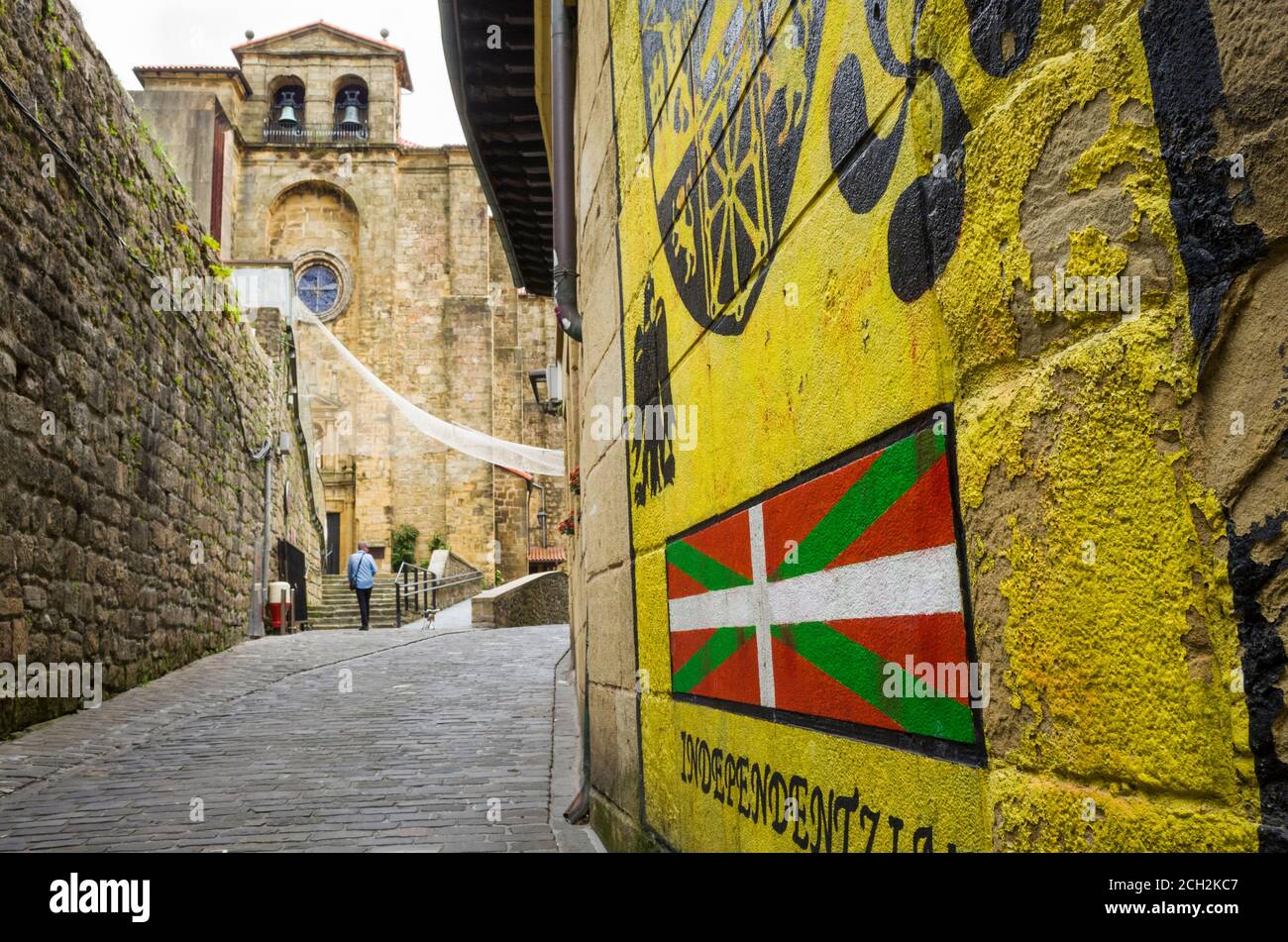 Pasajes, Gipuzkoa, Paesi Baschi, Spagna - 17 Luglio 2019 : Murale con bandiera ikurrina e chiesa di San Giovanni Battista in background. Foto Stock