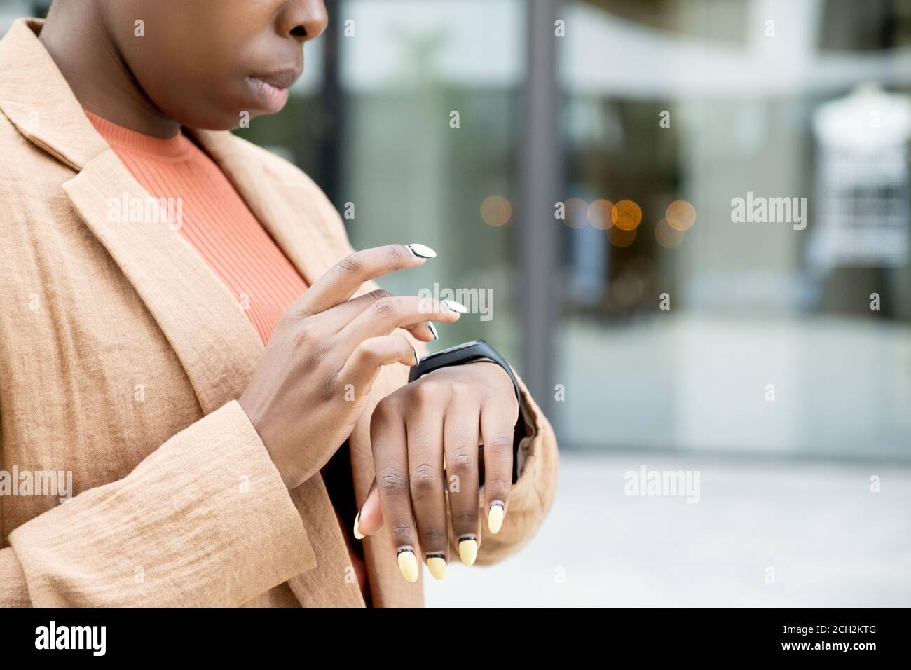 Mani di giovane donna africana in casualwear commovente display di smartwatch Foto Stock