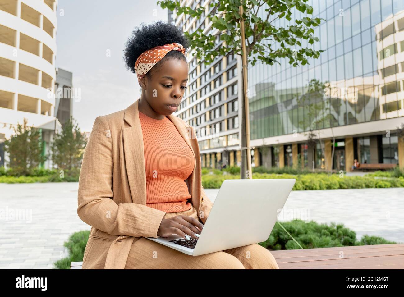 Giovane ed elegante donna d'affari di etnia africana con il laptop su di lei ginocchia Foto Stock