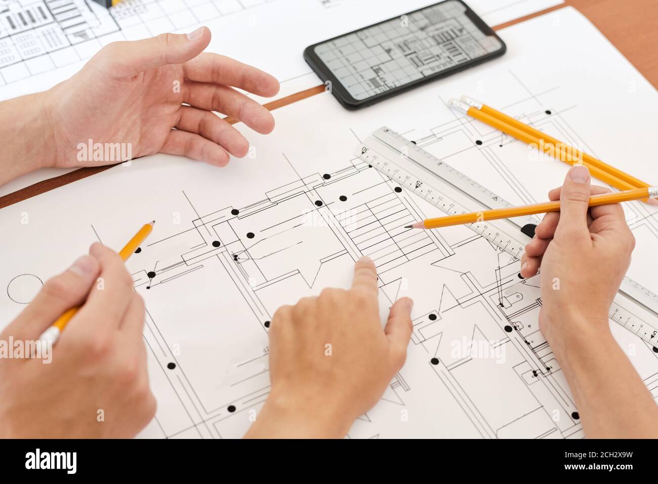 Mano di giovane ingegnere con matita che punta al dettaglio sopra schizzo di un nuovo edificio Foto Stock
