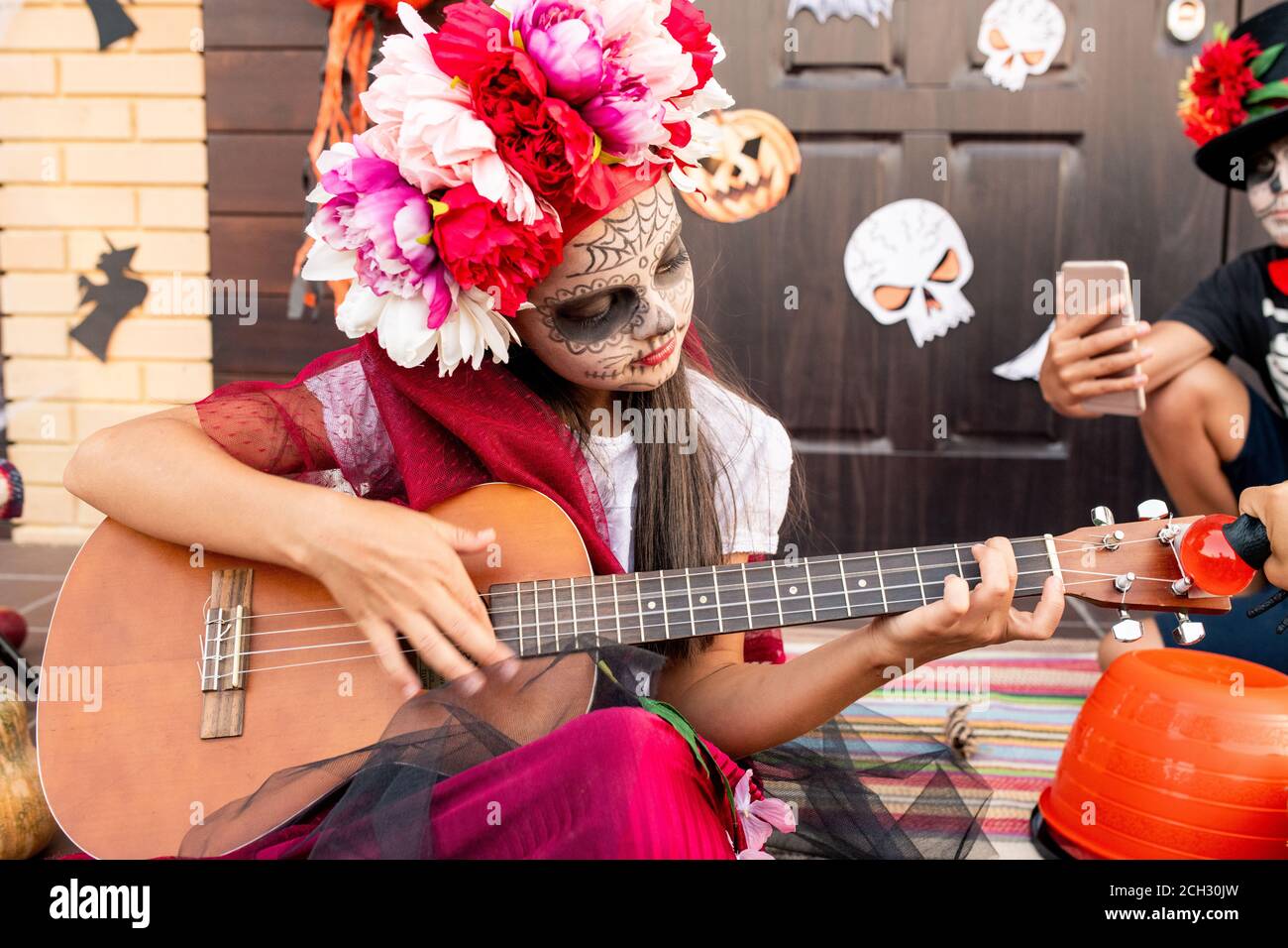 Cute bambina in costume di Halloween seduta su scala e. suonare la chitarra Foto Stock