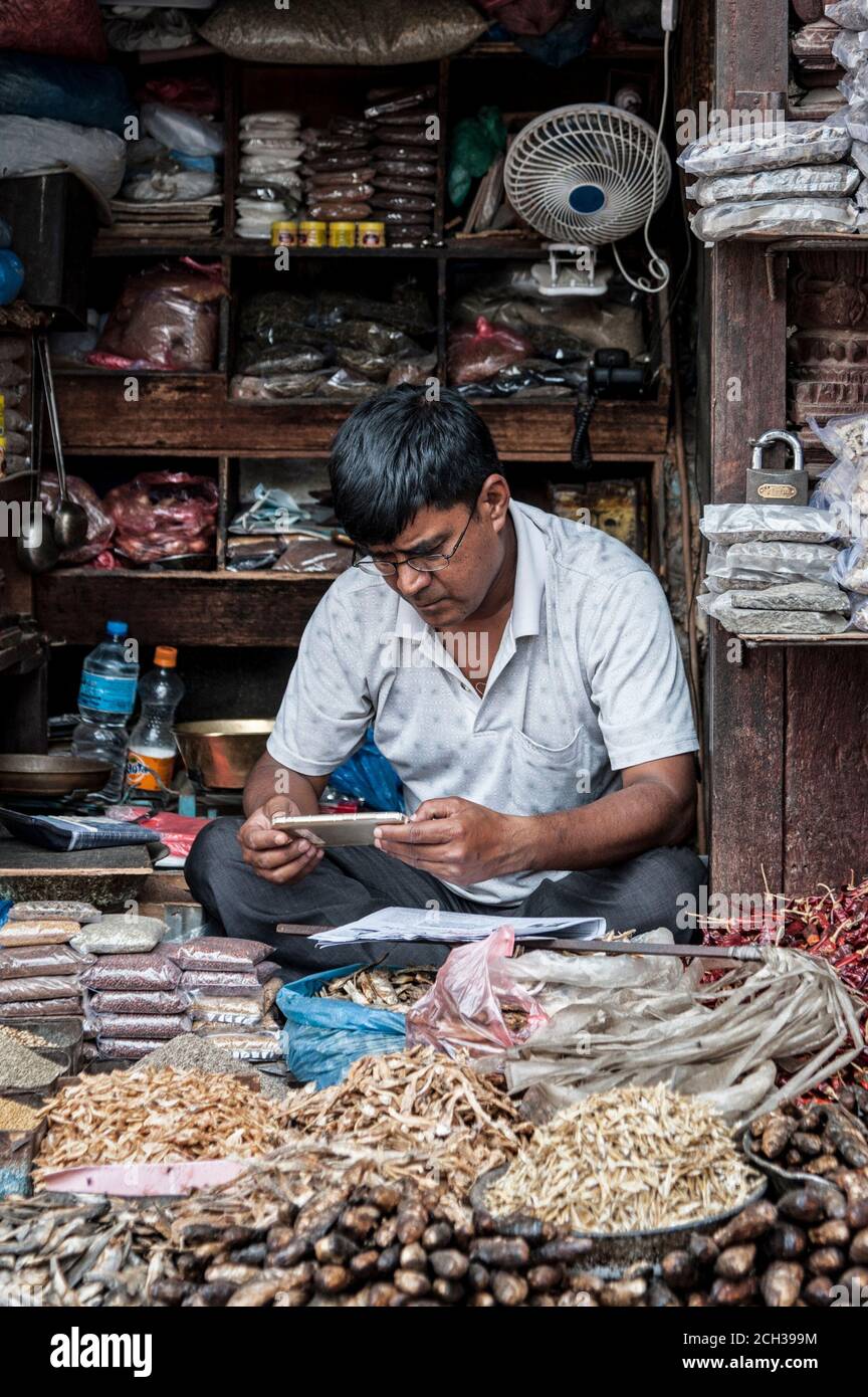KATHMANDU, NEPAL - 14 AGOSTO 2018: Uomo nepalese non identificato siede il suo negozio nella strada di Kathmandu, Nepal Foto Stock