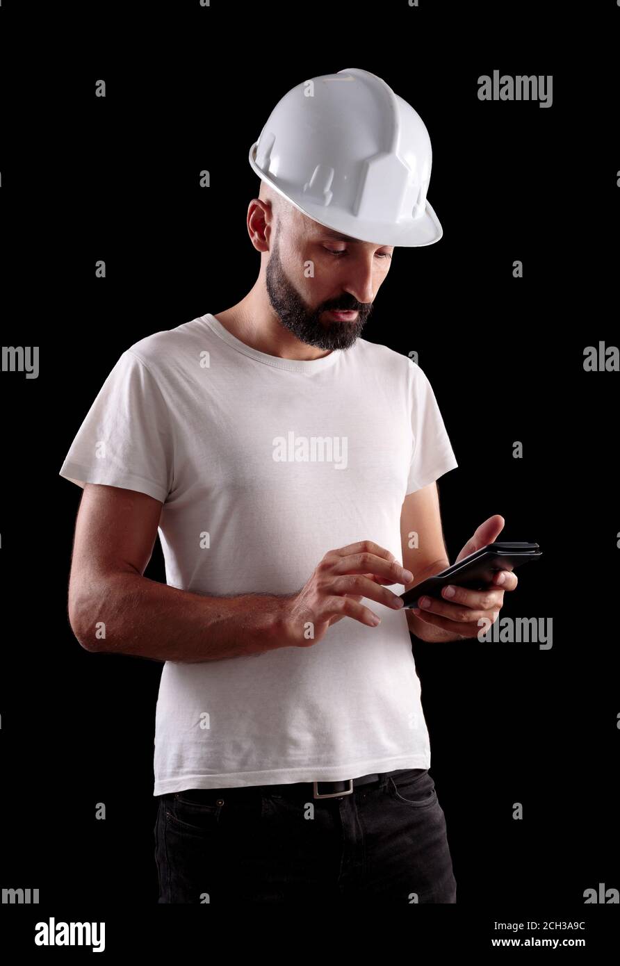 Giovane operaio di costruzione maschile esperto che guarda la sua calcolatrice Foto Stock
